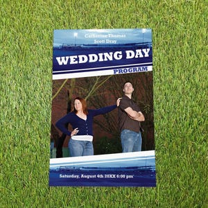 May include: A rectangular wedding day programme featuring a photograph of two people standing outdoors. The text reads Catherine Thomas, Scott Dray, WEDDING DAY PROGRAM, and Saturday, August 4th 20XX 6:00 pm, set against a blue and white background.