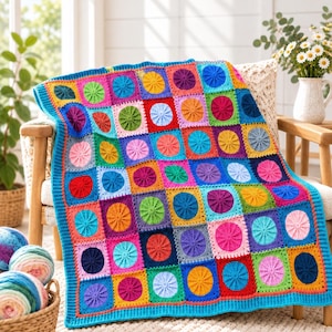May include: A handmade crochet blanket featuring a grid of colorful square motifs. Each square contains a raised, circular sunburst pattern in contrasting shades of red, blue, green, yellow, pink, purple, and orange, finished with a bright blue border.