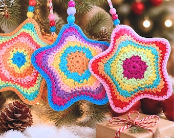 May include: Three star-shaped ornaments made of multi-colored crochet yarn. Each star features concentric rings of bright colors including pink, yellow, blue, and orange. The ornaments hang from strings decorated with small, round, multi-colored beads.