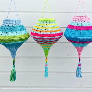 May include: Three crocheted hanging lamps with colorful stripes and tassels. The lamps are made of blue, green, pink, yellow, and orange yarn.