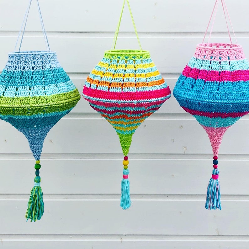 May include: Three crocheted hanging lamps with colorful stripes and tassels. The lamps are made of blue, green, pink, yellow, and orange yarn.