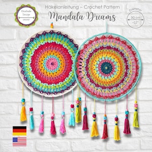 Op de afbeelding: Twee kleurrijke gehaakte mandala dromenvangers, ongeveer 30 cm in diameter, hangen tegen een witte bakstenen muur. Elke mandala heeft een levendig, concentrisch ontwerp met een verscheidenheid aan kleuren. Kwasten in verschillende kleuren hangen eronder.