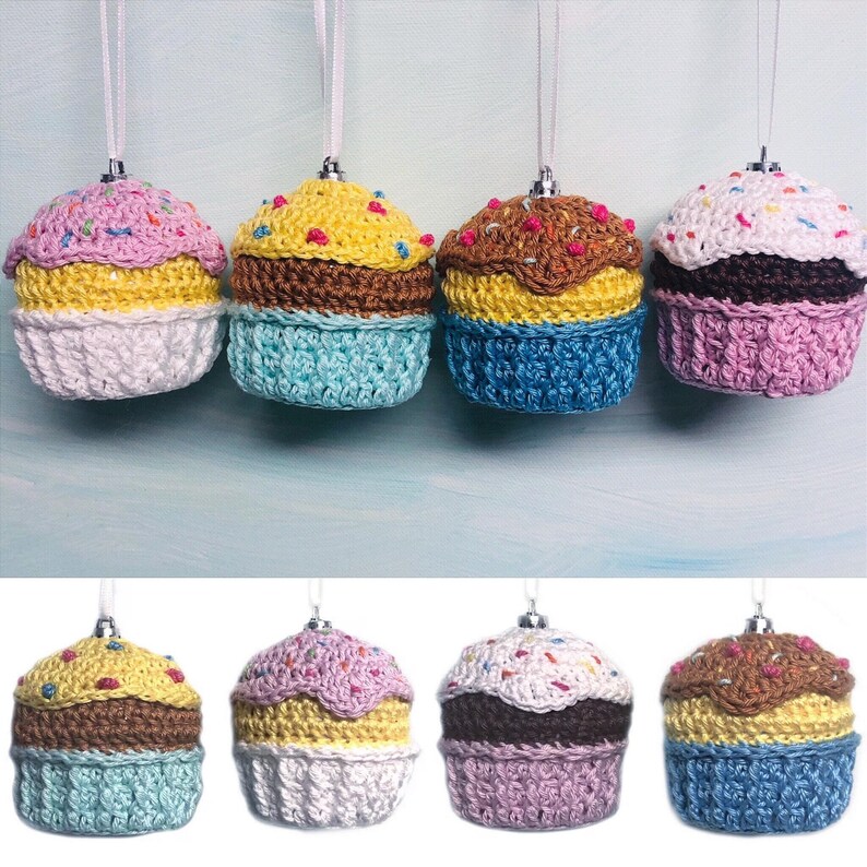 May include: A collection of eight crocheted cupcake ornaments, each featuring a unique color combination of yarn, a textured base, and a top decorated with small colorful sprinkles. Each ornament includes a silver cap and a white hanging ribbon.