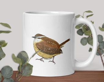 Puede incluir: Taza de cerámica blanca con una ilustración de un pájaro marrón y blanco. El pájaro está posado en una rama y tiene una cola larga.