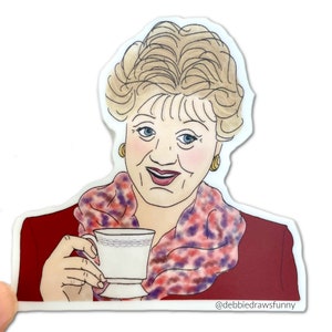 May include: A cartoon illustration of a woman with blonde hair wearing a red sweater and a purple and pink patterned scarf. She is holding a white teacup with a gold rim and a floral design.