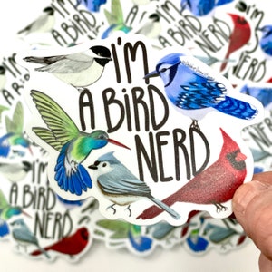 May include: A white sticker with the text "I'm a bird nerd" in black. The sticker features illustrations of a hummingbird, a blue jay, a cardinal, and a chickadee.