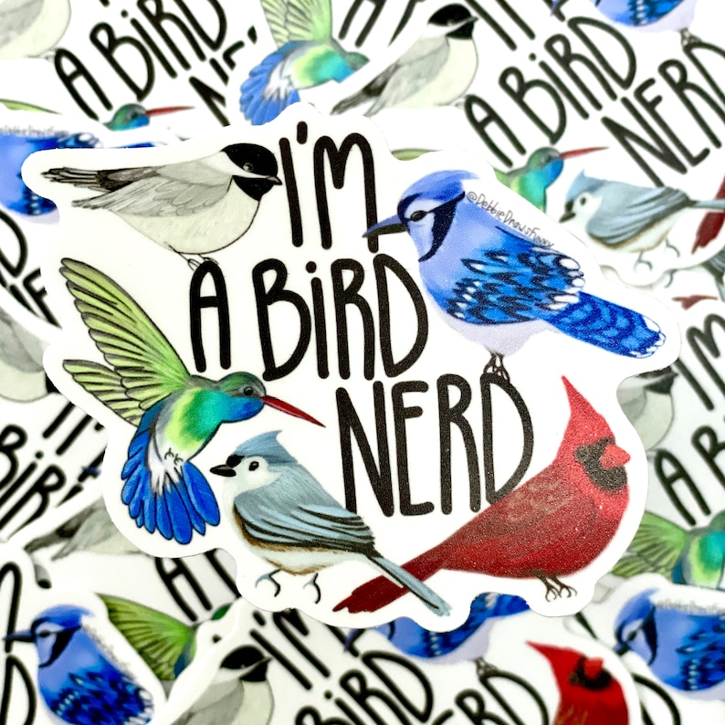 May include: A white sticker with the text "I'm a bird nerd" in black. The sticker features illustrations of five different birds: a blue jay, a hummingbird, a cardinal, a chickadee, and a black-capped chickadee.