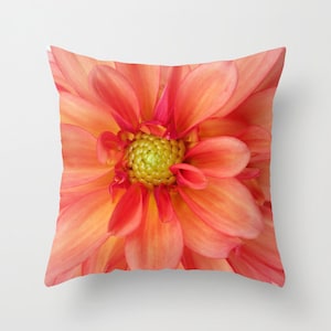 May include: Close-up of a vibrant orange dahlia flower with a yellow center. The petals are soft and delicate, creating a beautiful floral pattern.