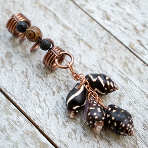 May include: Copper hair beads with black and brown wood beads, lava beads, and a chain with black and white seashells.