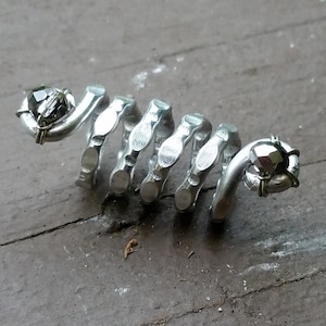 May include: A silver spiral ring with two black gemstones. The ring is made of metal and has a textured surface.