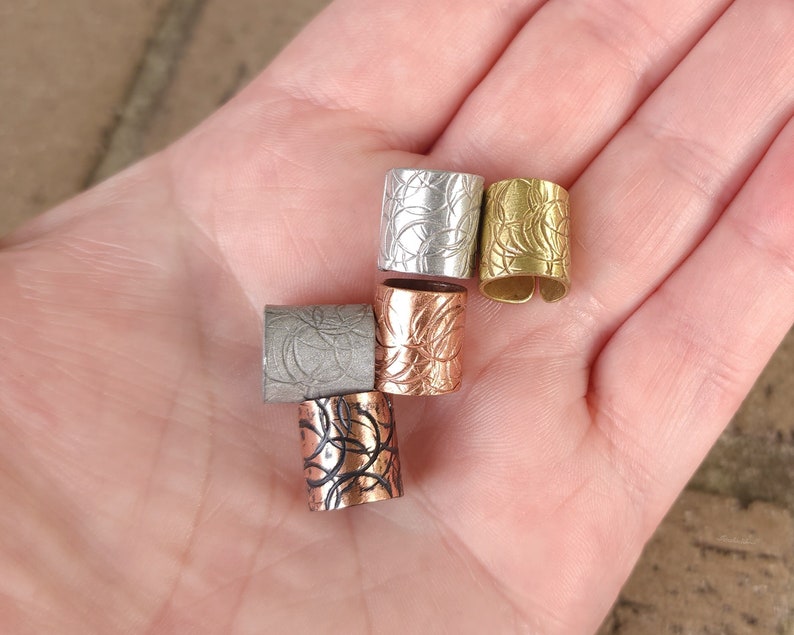 May include: Five decorative metal hair cuffs in different colors and patterns. The cuffs are silver, gold, copper, and black.
