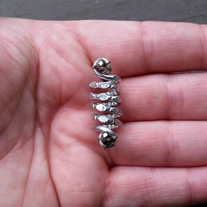 May include: A silver spiral ring with two black gemstones. The ring is made of metal and has a textured surface.