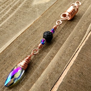 Puede incluir: Cuentas para el pelo envueltas en alambre de cobre con un cristal iridiscente, una cuenta de lava negra y cuentas de vidrio azul y morado.