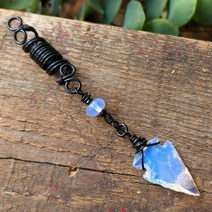 May include: Black wire hair wrap with a blue opal bead and a blue opal arrowhead charm.