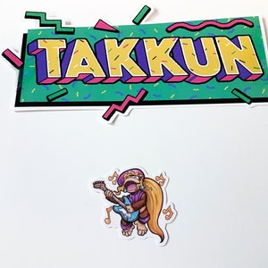 Puede incluir: Un juego de pegatinas con un personaje de dibujos animados tocando una guitarra azul, con notas musicales. El juego de pegatinas también incluye una pancarta con la palabra "TAKKUN" en letras amarillas con un contorno morado, sobre un fondo verde.