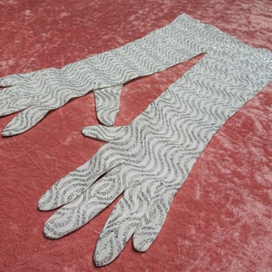 May include: A pair of long white gloves with a silver glitter wavy pattern.