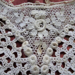 Puede incluir: Borde de encaje blanco tejido a crochet con un delicado patr&oacute;n floral y adornos circulares en relieve.
