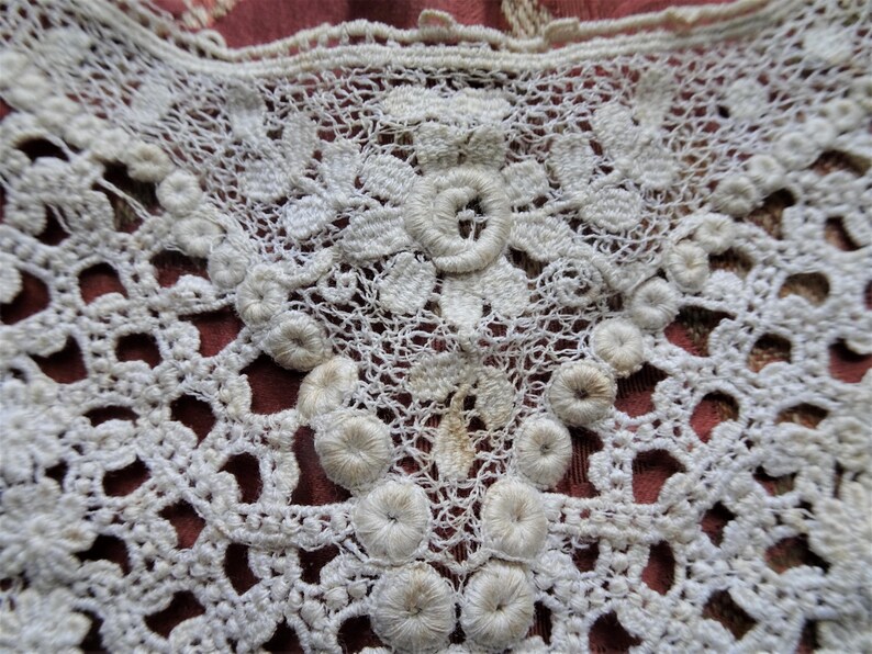 Puede incluir: Borde de encaje blanco tejido a crochet con un delicado patr&oacute;n floral y adornos circulares en relieve.