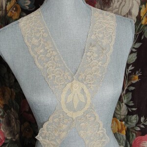 May include: A delicate white lace collar with a floral design. The collar is made of a fine, sheer fabric and has a delicate, feminine look.