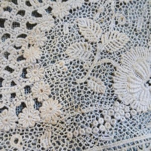 Puede incluir: Tela de encaje blanco de ganchillo con un delicado patr&oacute;n floral. El encaje presenta detalles intrincados y una textura delicada.