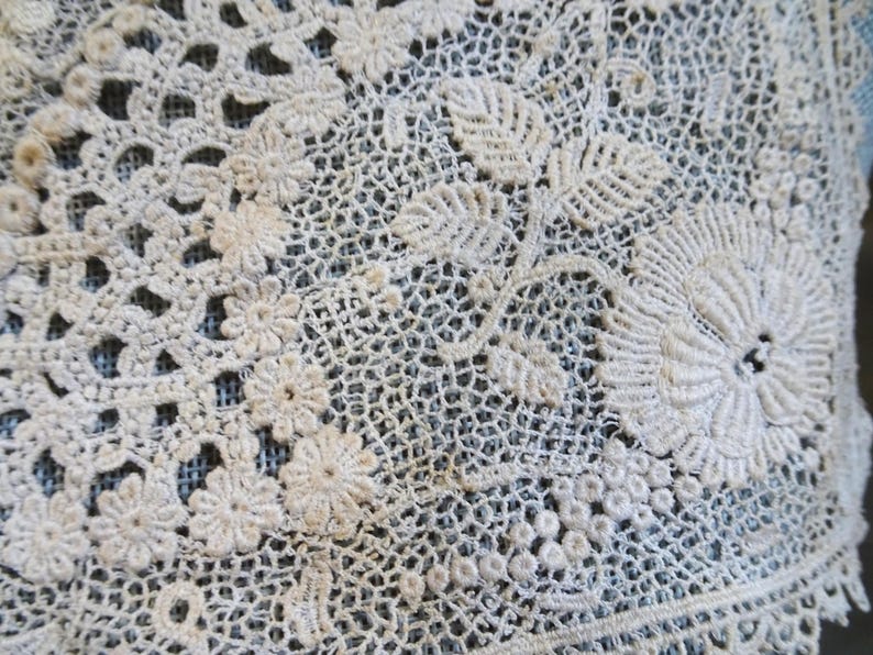 Puede incluir: Tela de encaje blanco de ganchillo con un delicado patr&oacute;n floral. El encaje presenta detalles intrincados y una textura delicada.