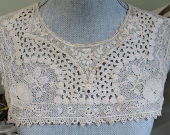 May include: A delicate white lace collar with a scalloped edge. The collar is made of intricate crochet work and features a floral design.