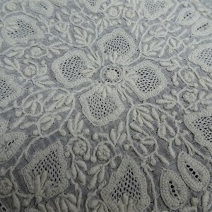 以下が含まれることがあります： 白い綿の生地に、複雑な白い花の刺繍が施されています。刺繍は細部まで丁寧に作られており、美しく上品なデザインになっています。