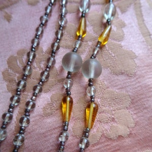 Peut inclure: Un collier multi-rangs avec des perles de verre transparentes et des perles en forme de larme de couleur ambre.