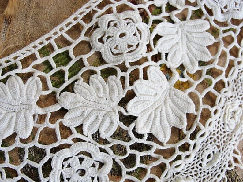 May include: White crocheted lace with a floral design. The lace has a delicate pattern of flowers and leaves.