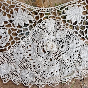 May include: White crocheted lace trim with a delicate floral pattern. The lace is made with a fine thread and has a scalloped edge.