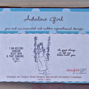 May include: A blue and white card with the text "Adaline Girl" and "pre-cut un-mounted red rubber repositional stamps". The card features a black and white illustration of a woman on a swing with the text "I am missing someone right now & that someone is you." and "the good things in life are better with you." The card also includes the text "angiegirl" and "stamps are larger than images shown-kit includes 3 stamps" and "ANGIE-1283A".