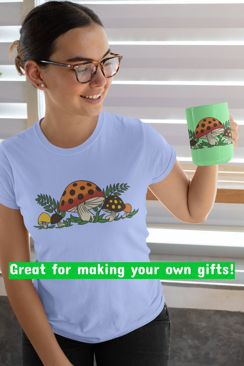 K&ouml;nnte beinhalten: Ein hellblaues T-Shirt mit einem Motiv von drei Pilzen in Braun-, Orange- und Gelbt&ouml;nen. Die Pilze sind von gr&uuml;nen Bl&auml;ttern umgeben. Der Text "Great for making your own gifts!" ist unten im Bild in Gr&uuml;n gedruckt.