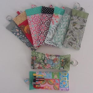 May include: Assortment of colorful fabric keychains with different patterns. Some keychains have a small pocket and a key ring.