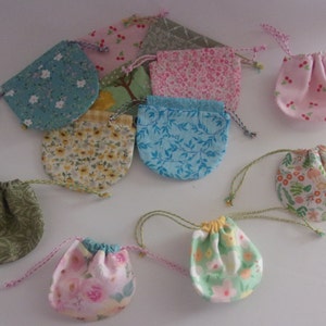 May include: Assortment of 10 small drawstring bags in various floral and patterned fabrics. The bags are made of cotton and have a variety of colors, including pink, blue, green, and yellow.