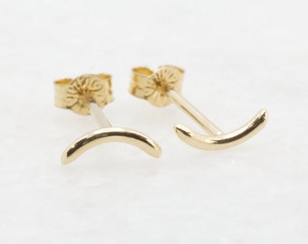 Può includere: Un paio di orecchini a lobo in oro a forma di mezzaluna. Gli orecchini sono piccoli e delicati, e hanno un design semplice e minimalista.