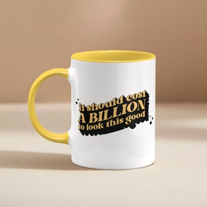 May include: White ceramic mug with a yellow interior and handle. The mug features the text "it should cost A BILLION to look this good" in a black and gold design. The mug is a standard size for coffee or tea.