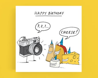 May include: A cartoon camera with a lens and legs is taking a picture of three cartoon cheese wedges wearing party hats. The camera says "3, 2, 1..." and the cheese says "CHEESE!" Happy Birthday.