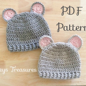 May include: Two gray crocheted hats with pink ears. The hats are on a wooden surface. The text "PDF Pattern" is written in black on a white background.