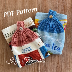 May include: Two crocheted dishcloths with buttons, one blue and one pink, on top of kitchen towels with the words "Coffee" and "For Tea".