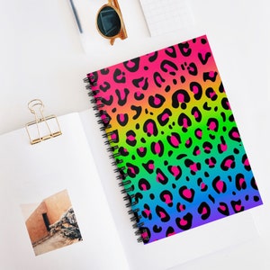 May include: A spiral bound notebook with a rainbow gradient background and a black leopard print pattern.