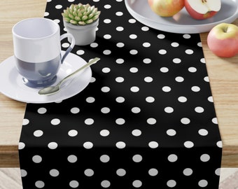 May include: Black and white polka dot table runner. The runner is made of a fabric material and has a repeating pattern of white circles on a black background.