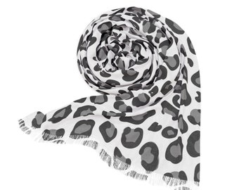 May include: A white scarf with a black leopard print pattern. The scarf is rolled up and has a fringed edge.