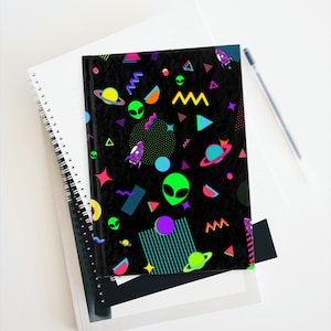 May include: A black notebook with a colorful 80s retro pattern featuring aliens, planets, and geometric shapes. The notebook has a spiral binding.