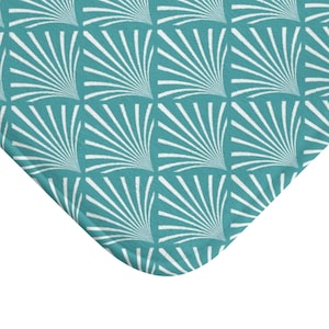 May include: A teal blue bath mat with a white geometric pattern of stylized sunbursts.