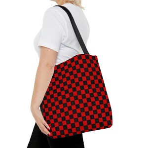 May include: A black and red checkered tote bag with black straps. The bag is made of canvas and has a large capacity.