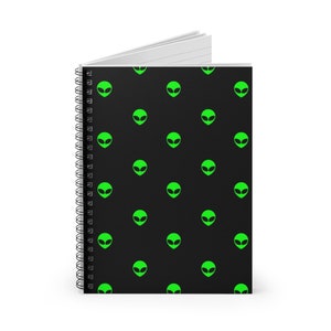 May include: A black spiral notebook with a repeating pattern of green alien heads.