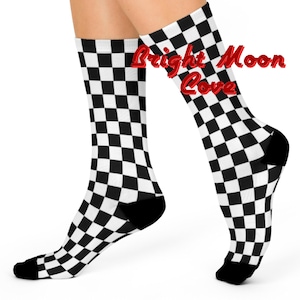 May include: A pair of black and white checkered socks with a black toe and heel. The socks have the text "Bright Moon Cove" written on them in red.