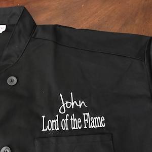 May include: Black chef's jacket with white embroidery that reads "John Lord of the Flame".
