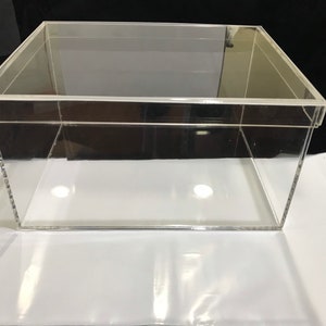 May include: A clear acrylic box with a lid. The box is empty and has a rectangular shape.