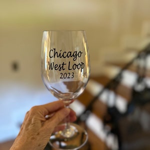 May include: A clear glass wine glass with the text "Chicago West Loop 2023" printed on the side.